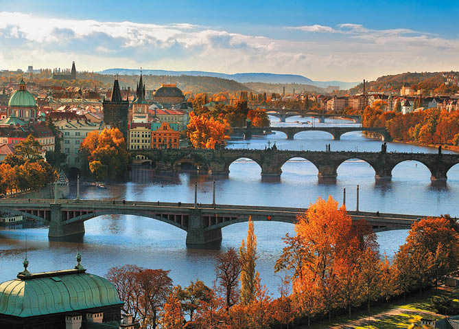 Podzimn panorama m sta s  ekou, n kolika historick mi mosty a stromy v tepl ch oran ov ch a  lut ch odst nech.  Popis generovan  AI