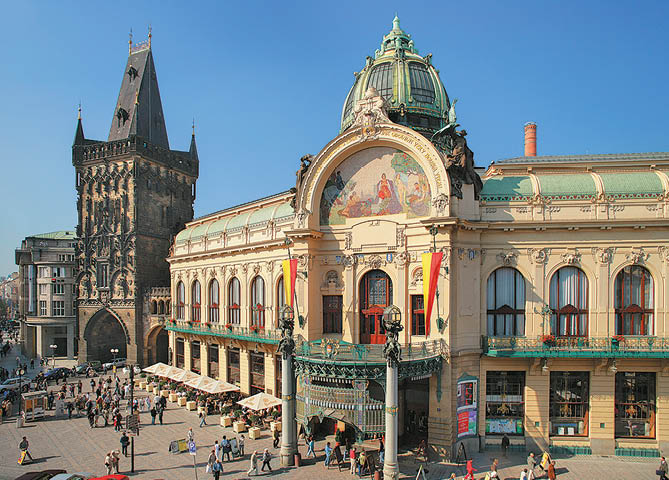 Historick budova s bohatou architekturou a barevnou freskou na pr  el  stoj  na ru n m n m st  pln m lid  za jasn ho slune n ho dne.  Popis generovan  AI