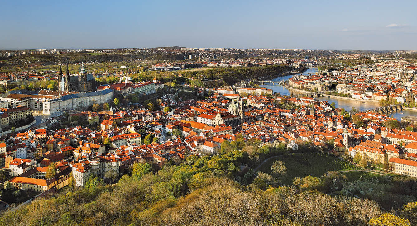 Panoramatick pohled na historick  m sto s  erven mi st echami,  ekou a zelen mi parky za slune n ho dne.  Popis generovan  AI