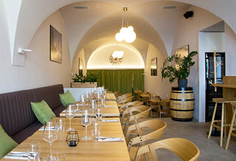 Modern restaurace s d ev n mi stoly a  idlemi, zelen mi pol t  i, z v sn m osv tlen m a dekorativn mi rostlinami v interi ru s obloukov m stropem.  Popis generovan  AI