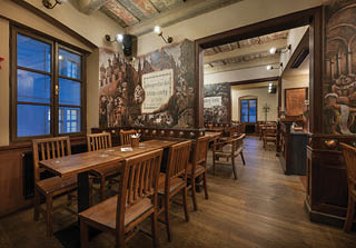 Interi r stylov restaurace s d ev n m n bytkem, malbami na st n ch a tepl m osv tlen m.  Popis generovan  AI
