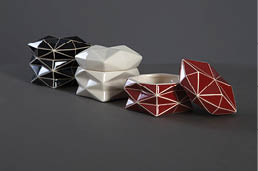 Geometrick keramick  n doby v  ern , b l  a  erven  barv  s b l mi linkami jsou uspo  d ny na tmav m povrchu.  Popis generovan  AI