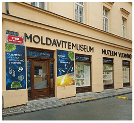 Fas da muzea s n pisy Moldavite Museum a Muzeum Vltav no s v lohami a plak ty propaguj c mi tajemstv a kr su drahokam  z vesm ru.  Popis generovan  AI