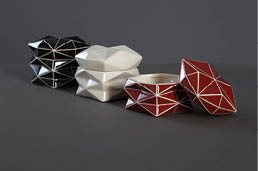 Geometrick keramick  n doby v  ern , b l  a  erven  barv  s b l mi linkami jsou uspo  d ny na tmav m povrchu.  Popis generovan  AI
